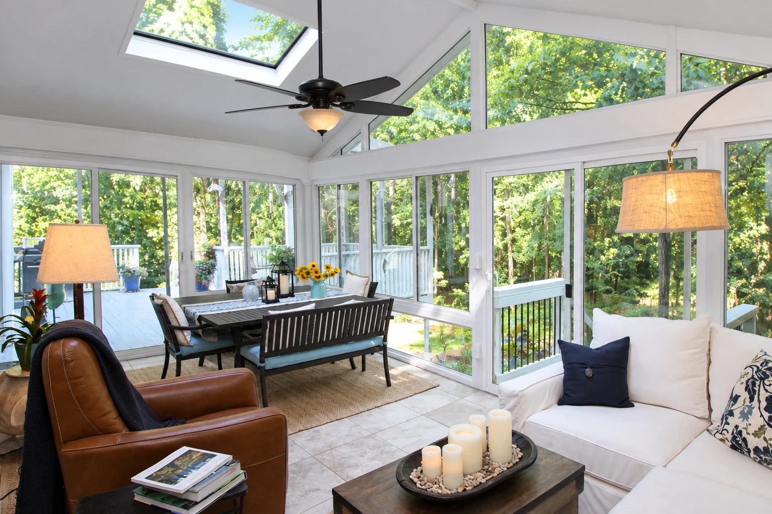 Bright vinyl sunroom with white-framed windows, a glass ceiling, dining set and seating overlooking leafy trees.